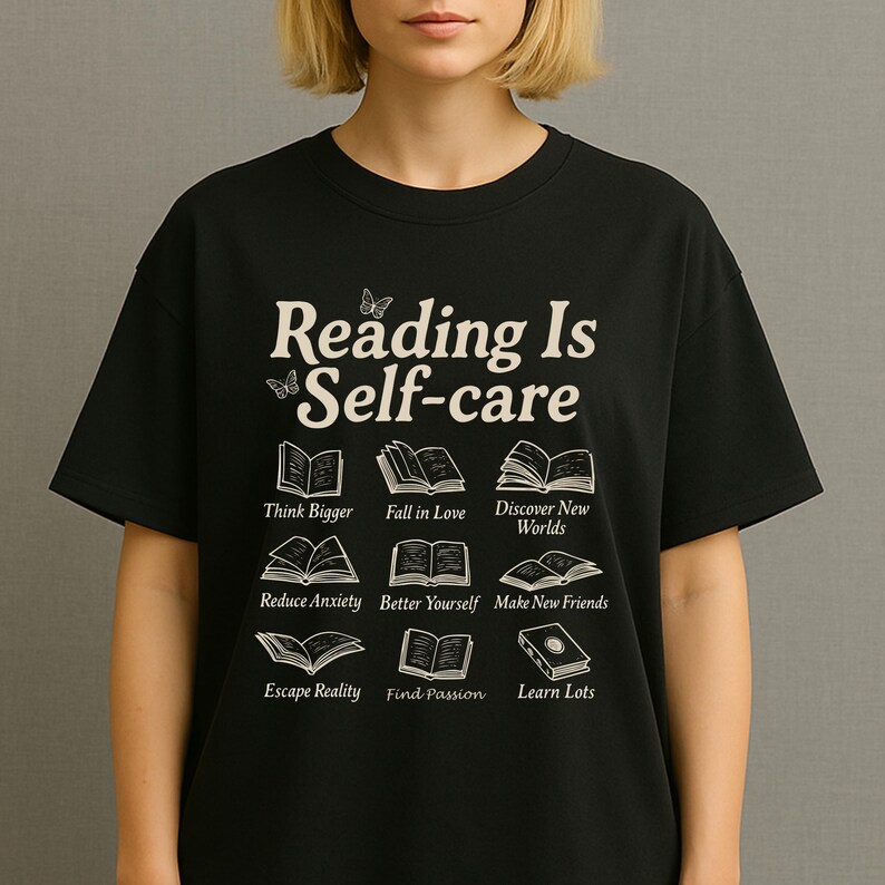 Puede incluir: Camiseta negra con la frase "Reading Is Self-care" e ilustraciones de libros. Debajo, se encuentran las frases "Think Bigger", "Fall in Love", "Discover New Worlds", "Reduce Anxiety", "Better Yourself", "Make New Friends", "Escape Reality", "Find Passion" y "Learn Lots".