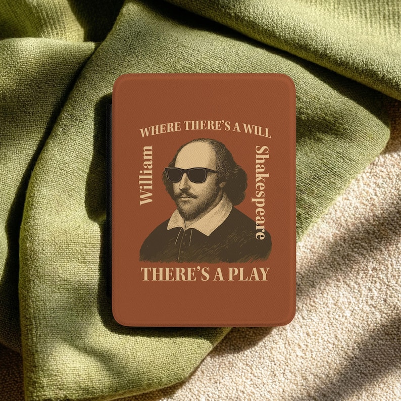 May include: A rectangular, rust-colored item featuring a portrait of William Shakespeare wearing sunglasses. Text reads "WHERE THERE'S A WILL, THERE'S A PLAY" and "William Shakespeare". The item is resting on a green cloth.