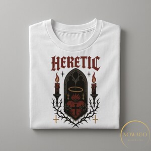 May include: White t-shirt with a gothic design featuring the word "HERETIC" in red, a heart with a cross, candles, and a halo. The design is framed by thorns and crosses, creating a dark aesthetic.