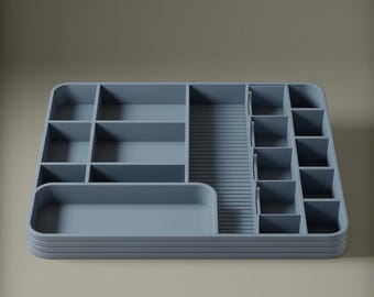 May include: A light blue desk organizer with multiple compartments and a tiered design. The organizer features various sized rectangular and square compartments, as well as a long, narrow section with vertical grooves. The overall design is modern and minimalist.
