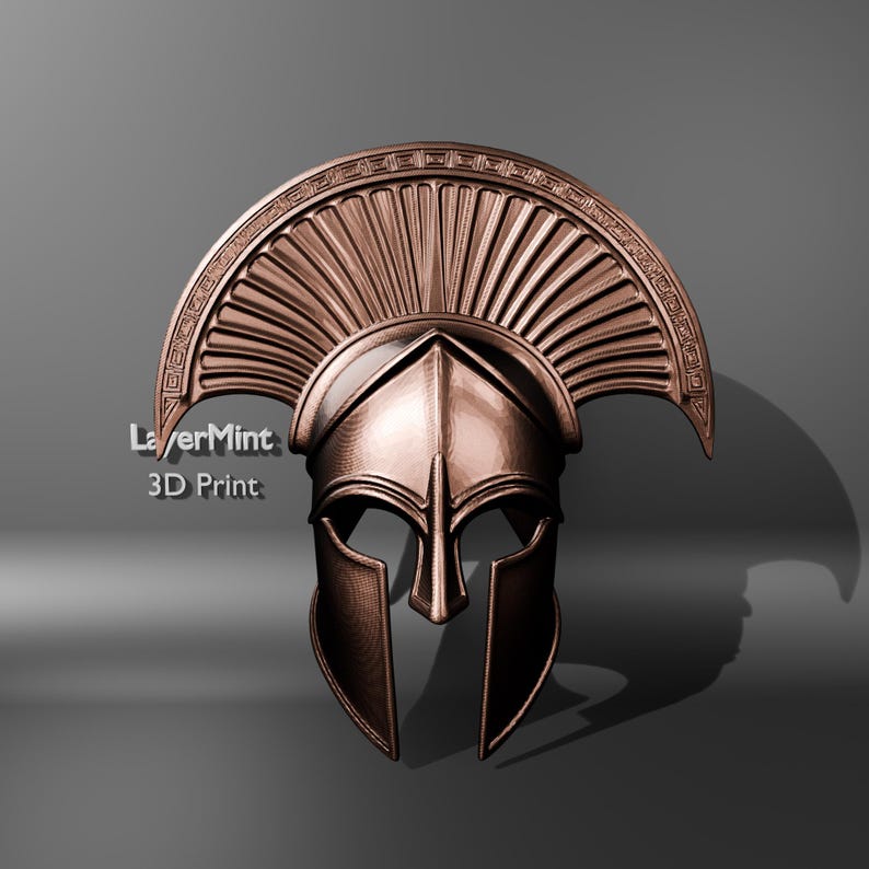 Puede incluir: Un casco espartano de color bronce con una cresta y una protecci&oacute;n facial detalladas. El casco tiene una superficie texturizada y se muestra sobre un fondo gris. El texto "LayerMint 3D Print" es visible en el lado izquierdo.