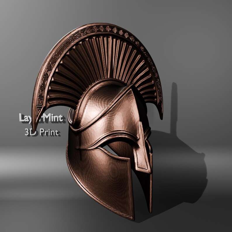 Puede incluir: Un casco espartano de color bronce con una cresta y una protecci&oacute;n facial detalladas. El casco tiene una superficie texturizada y est&aacute; sobre un fondo gris. El texto "Lay Mint 3D Print" es visible en el lado izquierdo.