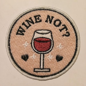 Può includere: Toppa ricamata con la scritta "WINE NOT?" in nero, che circonda un calice di vino pieno di liquido rosso. La toppa ha uno sfondo rosa chiaro con stelle bianche e cuori neri.