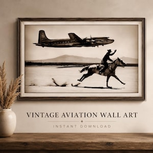 May include: A framed sepia-toned wall art print featuring a vintage propeller airplane flying low over a desert landscape while a person rides a horse at a gallop in the foreground. The image captures a contrast between aviation and equestrian travel.