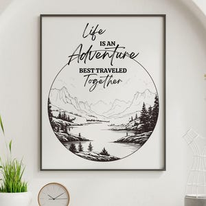 以下が含まれることがあります： 黒と白の印刷可能な壁の芸術。"人生は、一緒に旅する冒険です"という引用文が書かれています。引用文は、山脈と湖のイラストが描かれた円の中にあります。