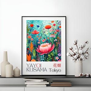 May include: A framed art print featuring a vibrant floral illustration. The artwork showcases a variety of colorful flowers in a lush garden setting, with text that reads "YAYOI KUSAMA Tokyo". The print is displayed on a white wall.
