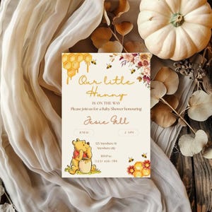 May include: A baby shower invitation with the text "Our little Hunny" and a Winnie the Pooh illustration. The invitation features a honeycomb design, flowers, and bees, with the date and time of the event.