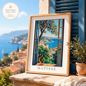 May include: A framed wall art print featuring a colorful painting of a coastal view through an open window, showing orange trees, a blue sea, and a town. The print includes the text MATISSE at the bottom, presented in a light wood frame.