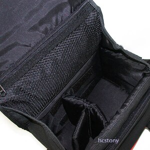 May include: A black camera bag with an open top, featuring a zippered mesh pocket on the underside of the lid, a main compartment with adjustable padded dividers, and the text hcstony printed in small white letters on the lower right side.