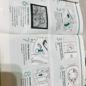 May include: A black and white illustrated guide with instructions on how to use a Canon camera. The guide shows how to attach a lens, set the focus mode, turn the command dial, focus the subject, take the picture, and unload the film.