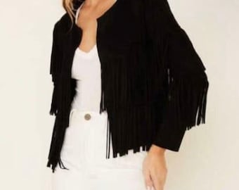 May include: A black suede jacket with fringe detailing. The jacket has a round neckline and long sleeves with fringe along the sleeves and hem. The jacket is open in the front and is paired with a white top and white pants.