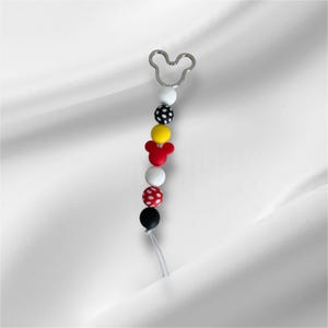 May include: A white phone charm with a silver Mickey Mouse head charm, black and white polka dot beads, red Mickey Mouse head bead, yellow bead, and white beads.