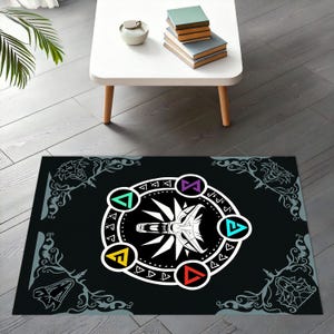 Puede incluir: Alfombra rectangular negra con un dise&ntilde;o gr&aacute;fico en blanco y negro que presenta una cabeza de lobo y formas geom&eacute;tricas coloridas. La alfombra tiene un borde decorativo con patrones florales grises. La alfombra est&aacute; sobre un suelo de madera.