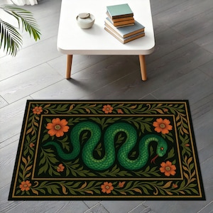 May include: A rectangular black rug with a green snake design, orange flowers, and green leaves. The snake is coiled and has a red tongue. The rug has a gold border and is on a grey wooden floor.