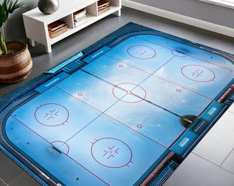 May include: A blue and white hockey rink rug with red lines and circles. The rug is oval shaped and has a centre circle and two face-off circles.