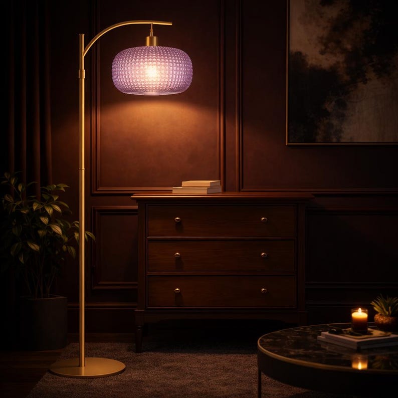 May include: A gold-colored floor lamp with a curved arm and a purple, textured lampshade. The lamp is in a room with dark wood paneling, a wooden dresser, and a round coffee table. A small plant is visible.