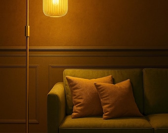 May include: A floor lamp with a gold finish and a ribbed glass shade illuminates a living room scene. The lamp stands next to a green sofa with two orange throw pillows. The room has a warm, inviting atmosphere.