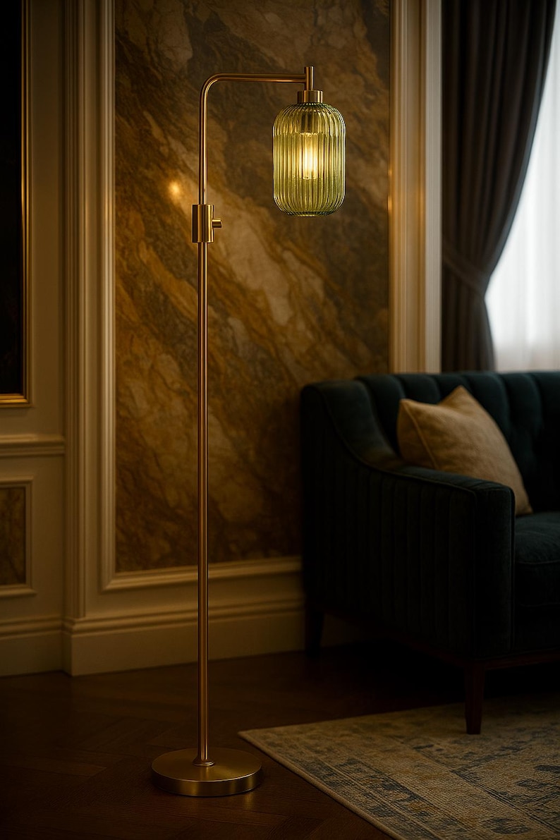 May include: A floor lamp with a slender brass-toned metal stand and a circular base. The lamp features a single downward-facing light source enclosed by a cylindrical, vertically ribbed, translucent olive green glass shade with a brass cap.