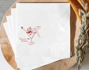 May include: White cocktail napkins with a red illustration of a woman in a martini glass, with the text "Tania's 30th Birthday" and "est. 1996". The napkins have a diamond pattern.