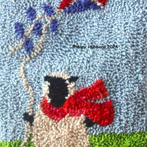 May include: A white sheep with a black face and red scarf is holding a blue, red, and white kite in a blue sky. The sheep is standing on green grass. ©Mary Hubbard 2024