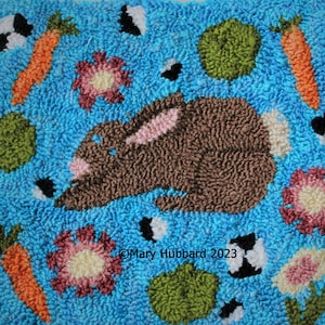 May include: A brown bunny rabbit with pink ears is surrounded by green, orange, and pink shapes on a blue background. The text "Mary Hubbard 2023" is in the lower center of the image.