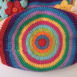 Puede incluir: Un c&iacute;rculo de crochet colorido con un patr&oacute;n de arco&iacute;ris. El c&iacute;rculo est&aacute; hecho de hilos de diferentes colores, incluyendo rojo, naranja, amarillo, verde, azul, &iacute;ndigo y violeta.