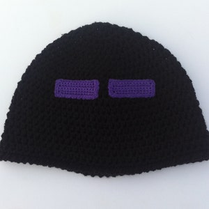 May include: Black crocheted beanie with purple eye details. The beanie is a popular Minecraft character.