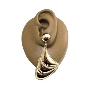 May include: Gold tone statement earrings with a large, layered, fan-shaped design.