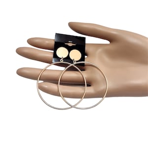 May include: A pair of gold hoop earrings with a small gold disc dangling from each hoop.