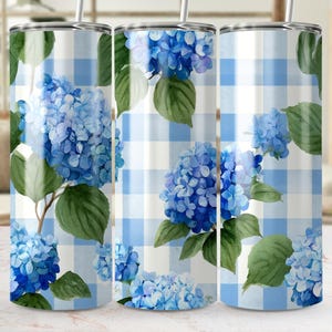 May include: Three stainless steel tumblers with a blue hydrangea floral design. The design features watercolor blue hydrangea blooms and green leaves on a light blue and white gingham background. Each tumbler has a silver lid and a straw.
