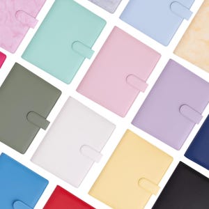 Può includere: Un assortimento di raccoglitori rettangolari colorati in vari colori pastello e tinta unita, tra cui rosa, verde, blu e giallo. Ogni raccoglitore ha una chiusura a fibbia abbinata.