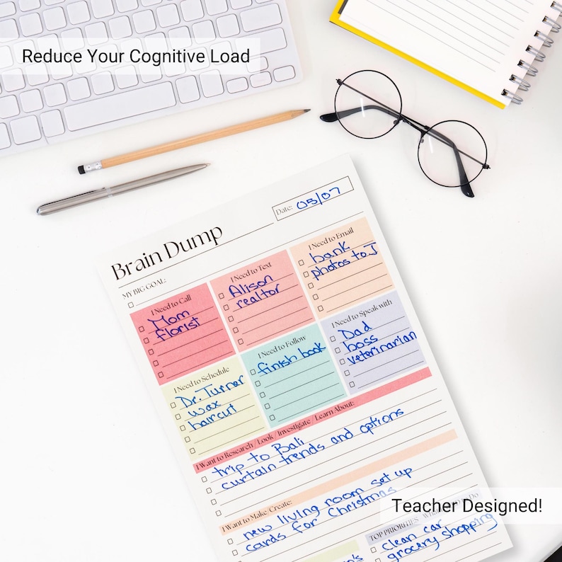 May include: A Brain Dump notepad with a list of tasks, including "Mom Florist" and "trip to Bali." The notepad is on a white surface with a keyboard, pen, pencil, and glasses. The text "Reduce Your Cognitive Load" is visible.