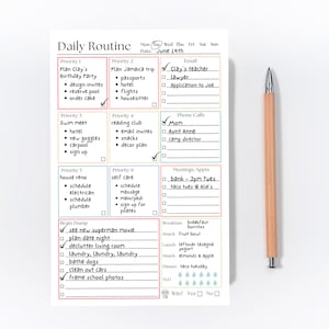 May include: A white daily routine planner notepad with colorful grid sections for priorities, email, phone calls, meetings, and a brain dump list, featuring handwritten tasks and checkmarks, accompanied by a light wood-toned mechanical pencil.