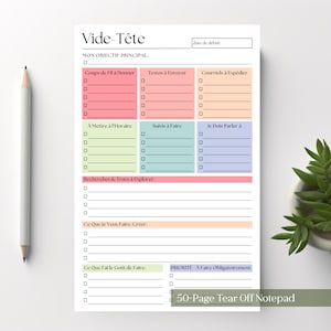 Könnte beinhalten: Ein weißer Notizblock mit farbigen Abschnitten für Notizen, darunter "Coups de Fil à Donner" und "Textos à Envoyer." Ein Bleistift liegt links. Der Notizblock trägt oben den Text "Vide-Tête" und unten "50-Page Tear Off Notepad".