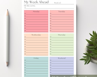Könnte beinhalten: Ein Wochenplaner-Block mit der Überschrift My Week Ahead und einem Bereich für My Big Goal. Die Seite enthält sechs farbige Abschnitte für Montag bis zum Wochenende, jeweils mit linierten Feldern und Checkboxen. Ein grauer Bleistift liegt links daneben.