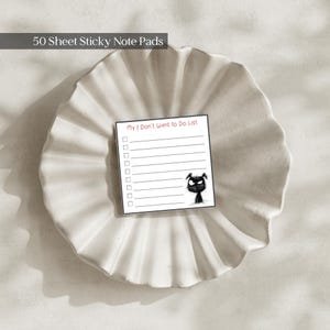 May include: A square sticky note pad with 50 sheets, featuring the text My I Don't Want to Do List at the top, a series of checkboxes with horizontal lines, and a small, sketchy black cat illustration in the bottom right corner.