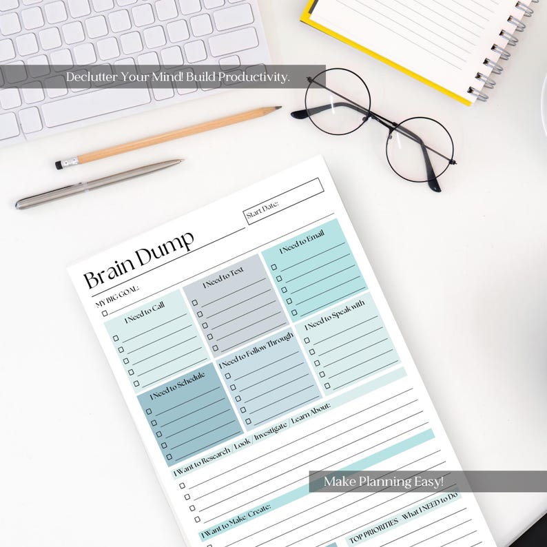 May include: A white notepad with a teal and gray layout for planning and organization. The notepad includes sections for tasks like calls, emails, and scheduling, with the text "Brain Dump" at the top. A pencil, pen, glasses, and keyboard are also visible.