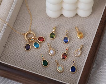 May include: A gold-colored necklace with a large circular clasp and multiple gemstone pendants. The pendants are oval-shaped and feature various colors, including red, blue, green, and purple. Additional gemstone pendants are displayed separately.