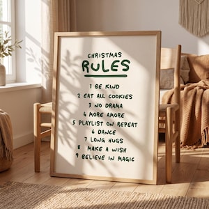 Könnte beinhalten: Ein gerahmtes vertikales Poster mit hellcremefarbenem Hintergrund und dunkelgrünem, handgeschriebenem Text: CHRISTMAS RULES, 1 BE KIND, 2 EAT ALL COOKIES, 3 NO DRAMA, 4 MORE AMORE, 5 PLAYLIST ON REPEAT, 6 DANCE, 7 LONG HUGS, 8 MAKE A WISH, 9 BELIEVE IN MAGIC.
