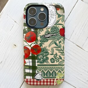 May include: A smartphone case featuring a collage-style design with red tomatoes on a green checkered background, a small fish illustration, a hummingbird, and intricate green floral patterns on a cream base, finished with a red and white checkered border.