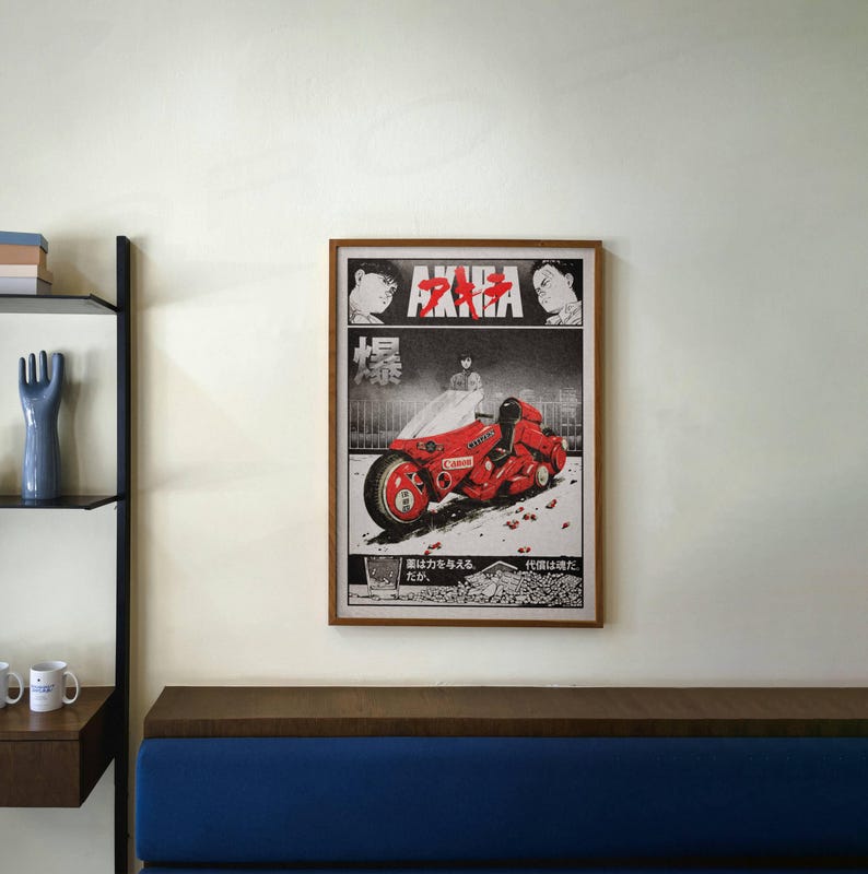 May include: Framed poster featuring a vibrant red motorcycle from the anime film "Akira." The artwork is in a manga style, with Japanese text and imagery. The poster is encased in a wooden frame and mounted on a white wall.