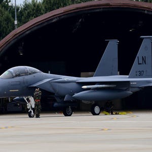 Puede incluir: Un avión de combate gris con el número de cola "LN 317" está estacionado frente a un hangar. El avión tiene una gran cabina gris oscuro y un fuselaje largo y estrecho. El avión está sentado en una pista con algunas personas de pie cerca.