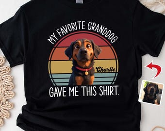 May include: Black t-shirt with a graphic of a dog inside a sunset design. Text reads "MY FAVORITE GRANDDOG GAVE ME THIS SHIRT." The dog's name, "Charlie," is also displayed. The shirt is a Gildan brand.