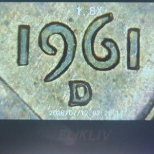 May include: A close-up view of a metallic coin surface featuring the embossed date 1961 and the mint mark D. The image includes digital overlay text showing 1.8X magnification and a timestamp of 2026/07/12 at the bottom of the frame.