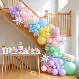 May include: A balloon garland in pastel shades of pink, blue, yellow, green, and purple, featuring star-shaped foil balloons, cotton candy-shaped balloons, and rectangular foil balloons with the text TICKET ADMIT ONE.