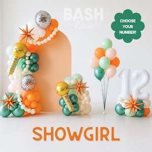 May include: A party decoration set featuring balloon arrangements in orange, green, white, and gold. Includes a balloon arch, microphone-shaped balloons, starburst accents, and a number 12 balloon display. The word "SHOWGIRL" is displayed in orange text.