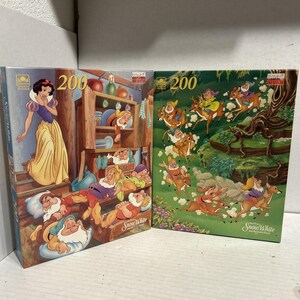 以下が含まれることがあります： 200ピースの白雪姫パズル2つ。1つは白雪姫と7人の小人をコテージのシーンで描いています。もう1つは、森の中で鹿に乗る小人たちを描いています。どちらの箱にもディズニーの白雪姫のロゴが入っています。