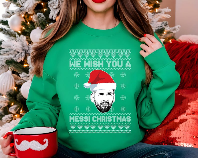 Puede incluir: Jersey navide&ntilde;o verde con el texto "WE WISH YOU A MESSI CHRISTMAS" y un gr&aacute;fico de Lionel Messi con un gorro de Pap&aacute; Noel. El jersey tiene un dise&ntilde;o festivo, perfecto para la temporada navide&ntilde;a.