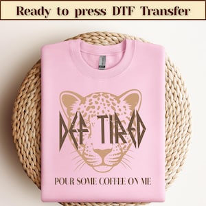 May include: Pink sweatshirt with a brown leopard print design and the text "DEF TIRED POUR SOME COFFEE ON ME".