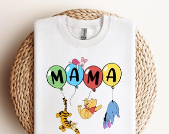 May include: White t-shirt with a colourful "MAMA" graphic featuring Winnie the Pooh and his friends holding balloons.